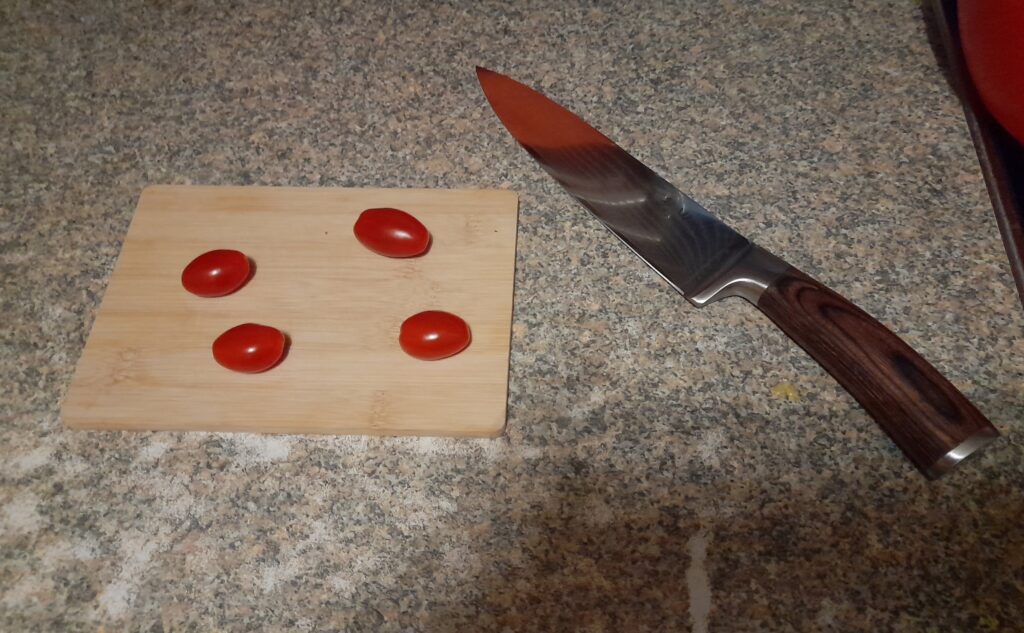 Wakoli Edib Damast Chefmesser liegt neben Schneidebrett Tomaten auf Brett